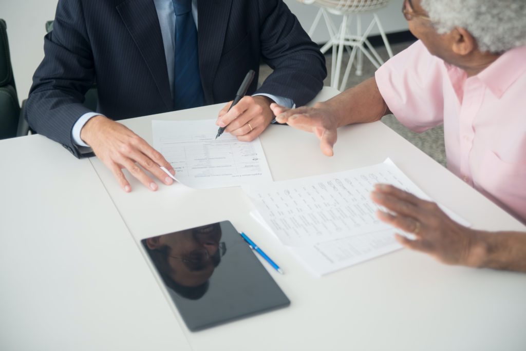 Insurance agent sitting with and explaining insurance coverage to an elderly person.